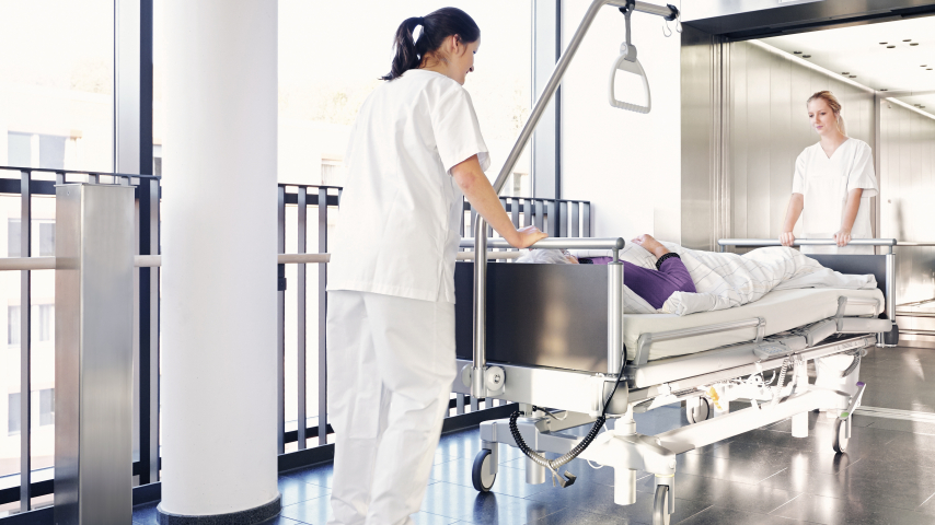 پرستاران با یک بیمار در اطراف تخت بیمارستان قدم می زنند