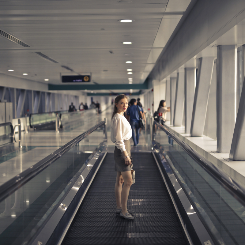 زنی روی پله برقی در یک ساختمان ایستاده است