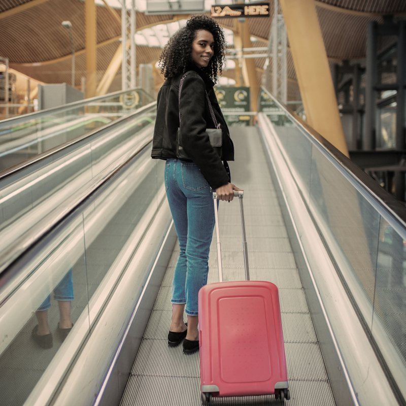 زن با چمدان روی پله برقی در یک ساختمان